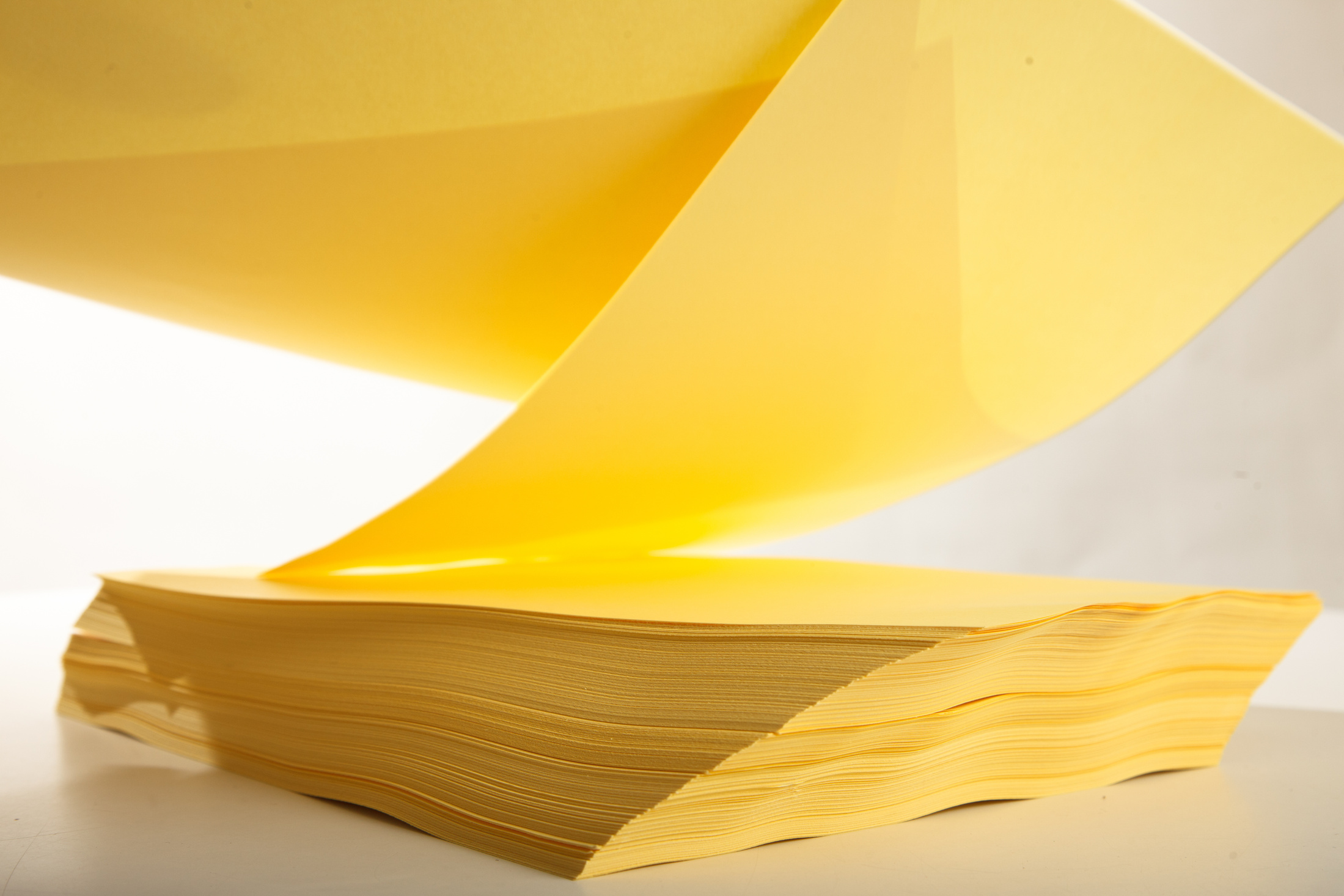 Sheets of yellow printer paper falling on white background.